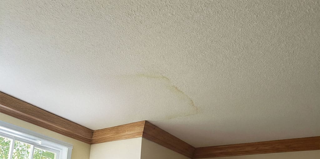 Interior ceiling water stain caused by a roof leak discovered during a storm damage roof inspection